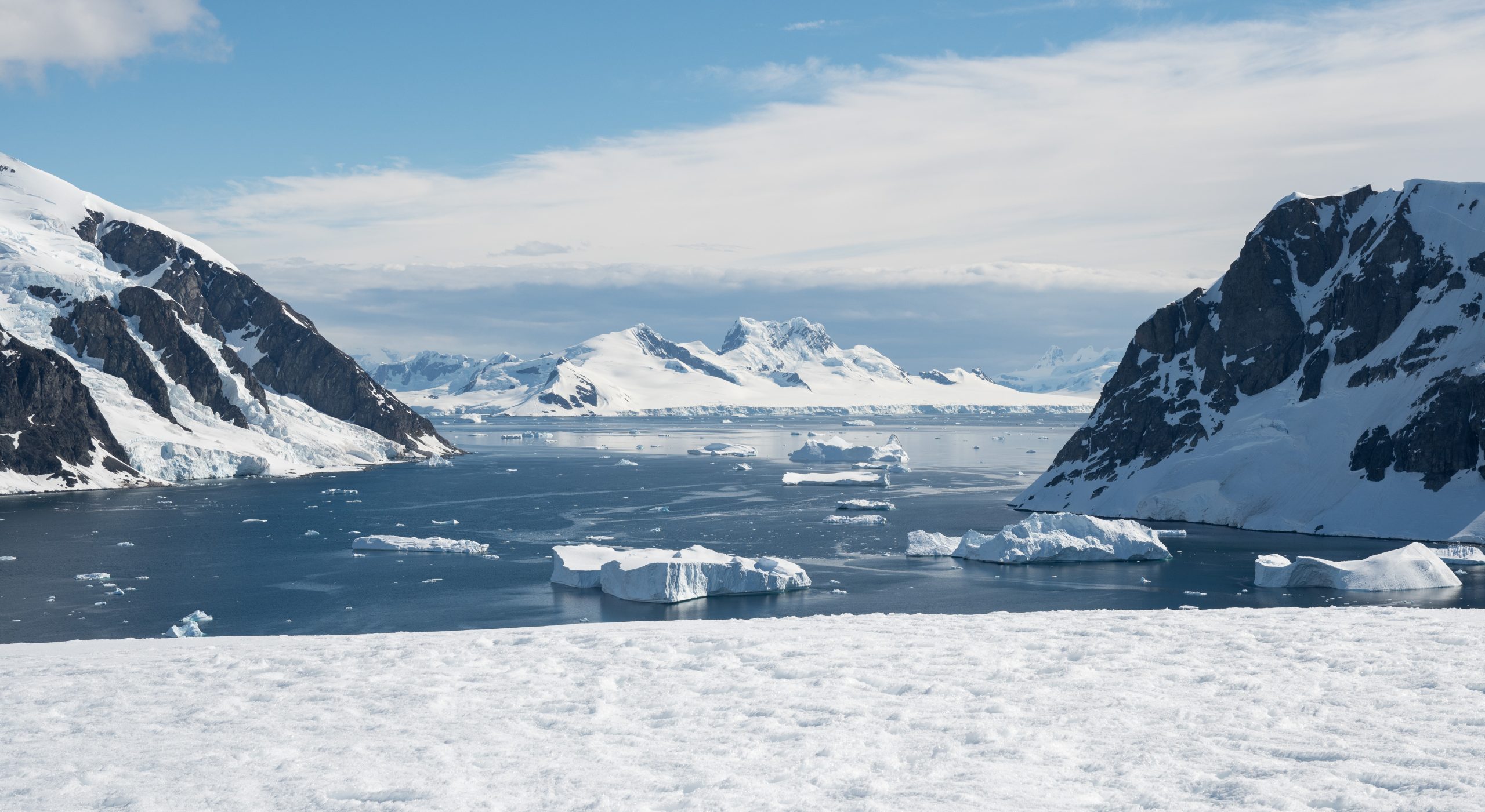 Rugged snow covered mountains and icebergs at the Antarctic Peninsula.