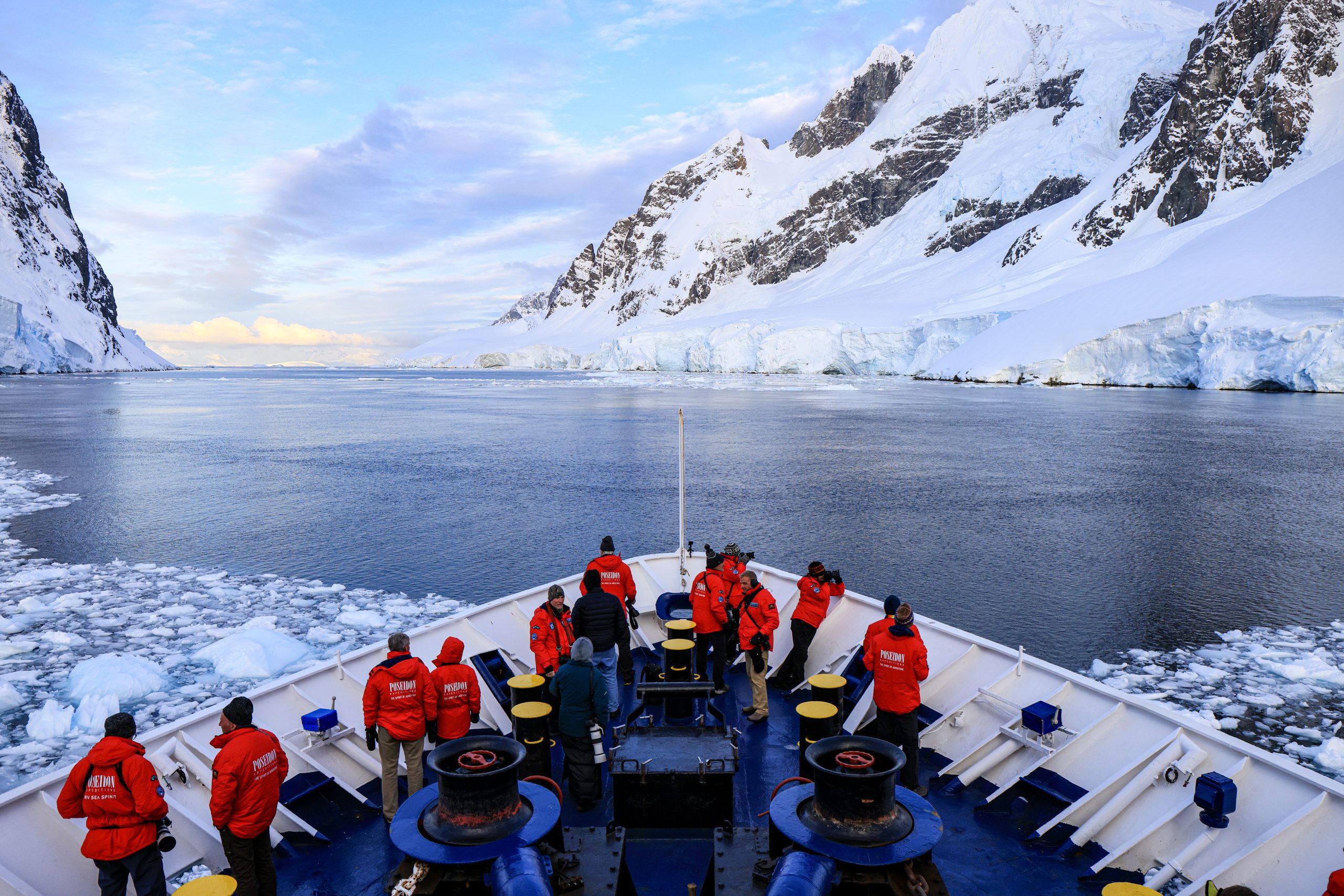 Guest standing on bow of ship sailing through narrow strait.