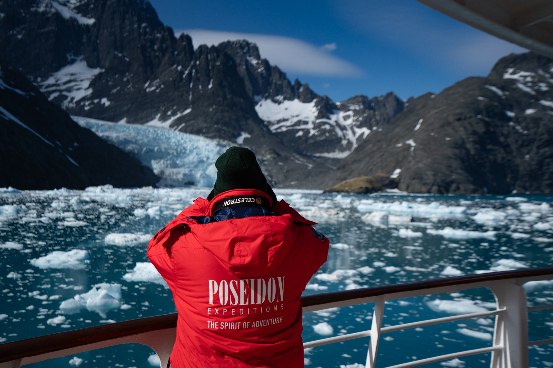 Passenger standing on deck looking at icy landscape.