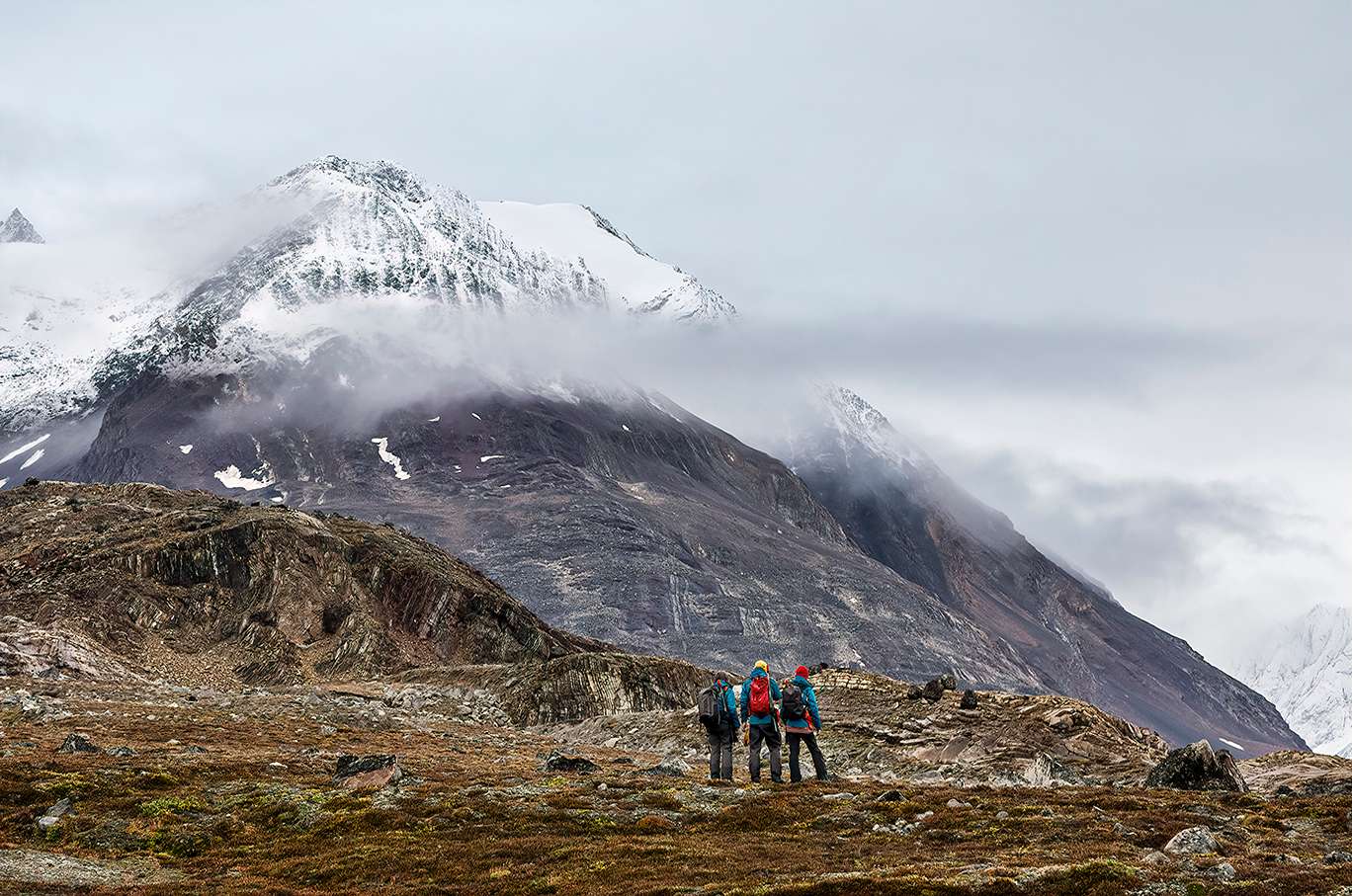 Guests hiking the tundra with dramatic mountain peak in background.