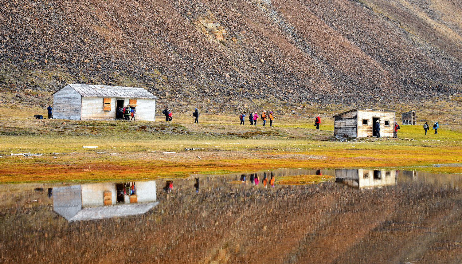 Guests walking on shore near huts.