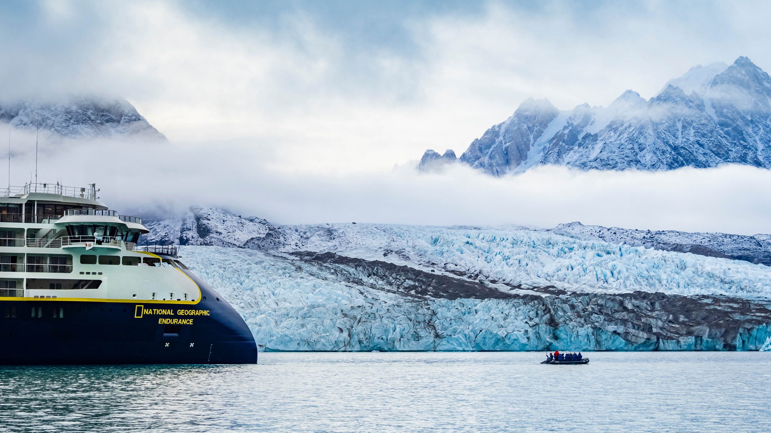 The bow of National Geographic Endurance pointed toward zodiac in the water.