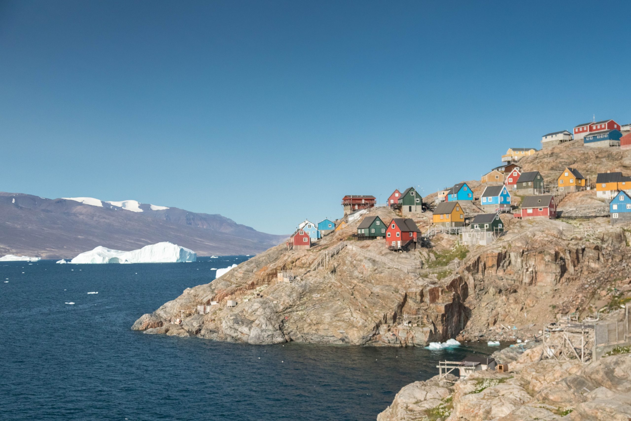 Colorful houses on rocky shoreline in Uumannaq on West Greenland.